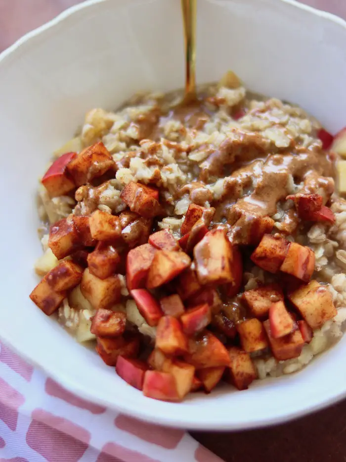 mingau de aveia vegano com maçã, canela servido em uma cumbuca com pasta de amêndoas caseira