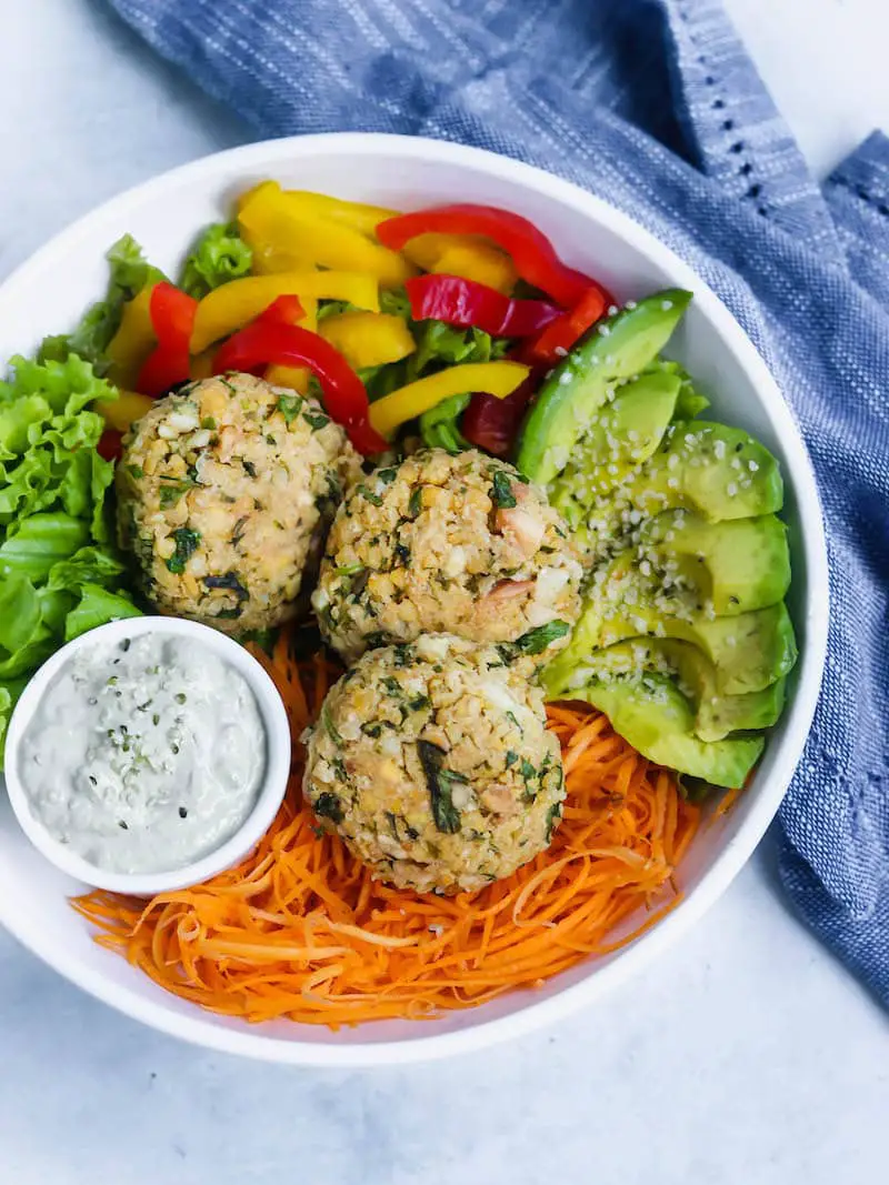 hambúrguer de grão de bico vegano servido em um prato com saladas