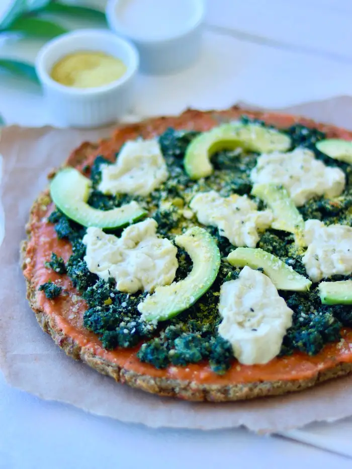 pizza vegana com massa de couve flor e creme de folhas de cenoura, queijo cremoso vegano, avocado e parmesão vegano