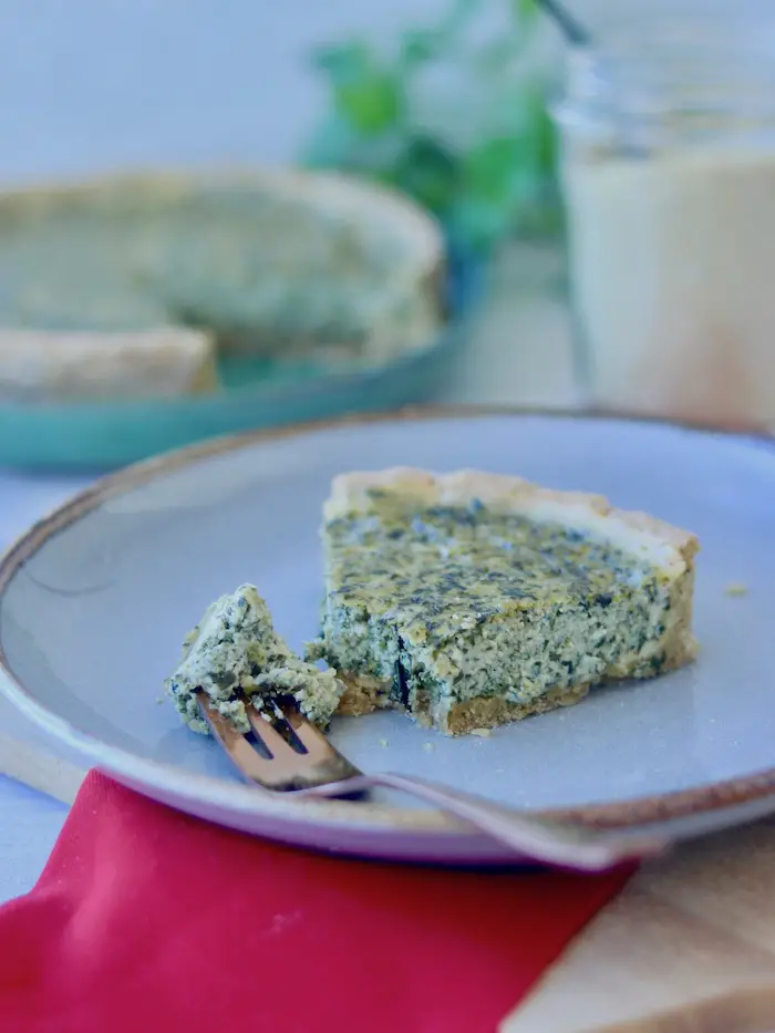 fatia de torta cremosa de tofu e folhas de cenoura servida em um prato