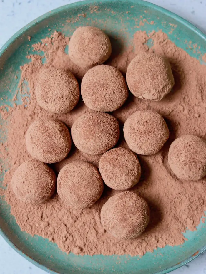 trufas veganas de nutella servidas em um prato com cacau em pó