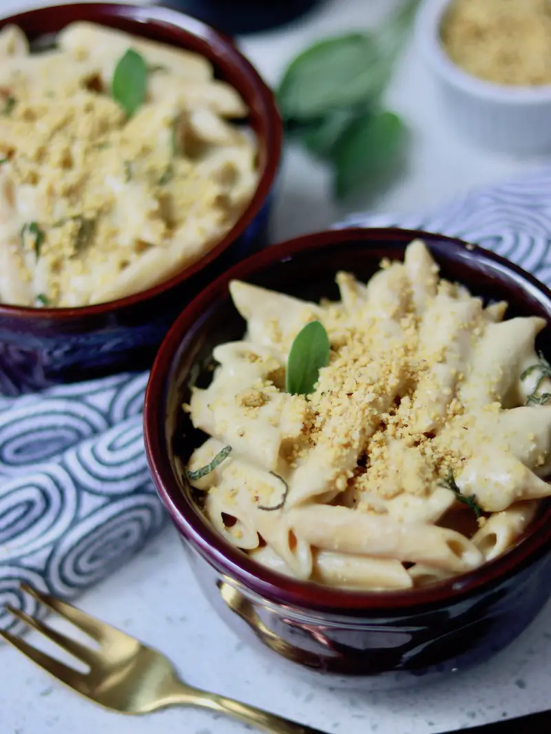 mac and cheese vegano servido em uma cumbuca com parmesão vegano e sálvia