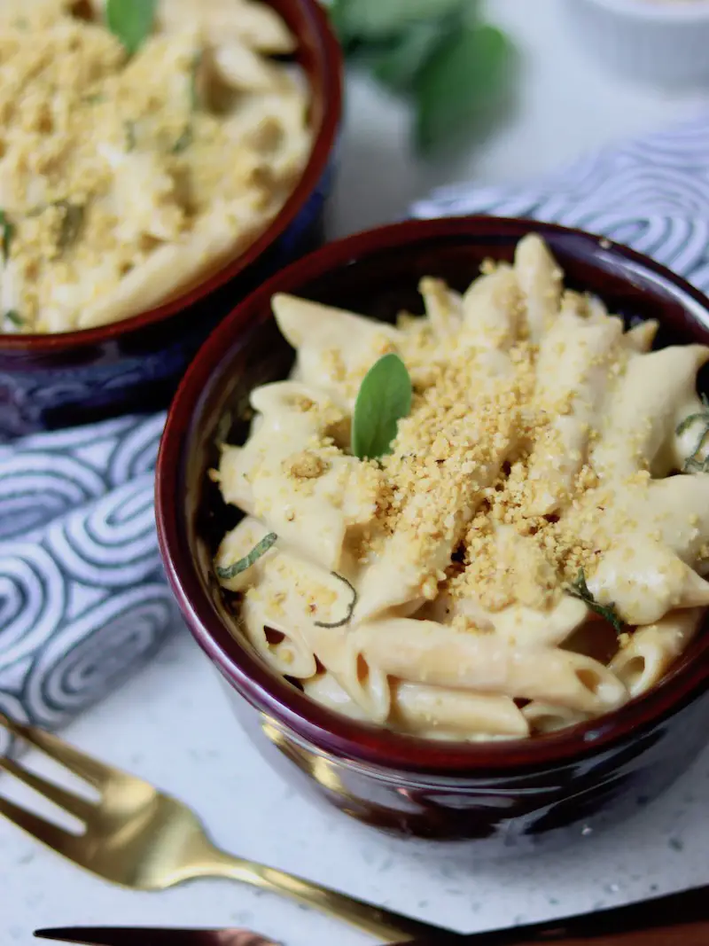 mac and cheese vegano servido em uma cumbuca com parmesão vegano e sálvia