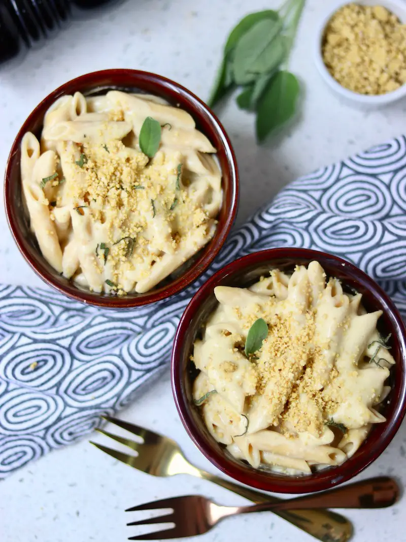mac and cheese vegano servido em uma cumbuca com parmesão vegano e sálvia