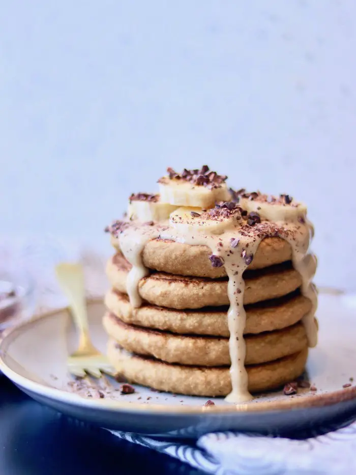 panqueca vegana de aveia e banana servida com creme de pasta de amendoim, banana e nibs de cacau