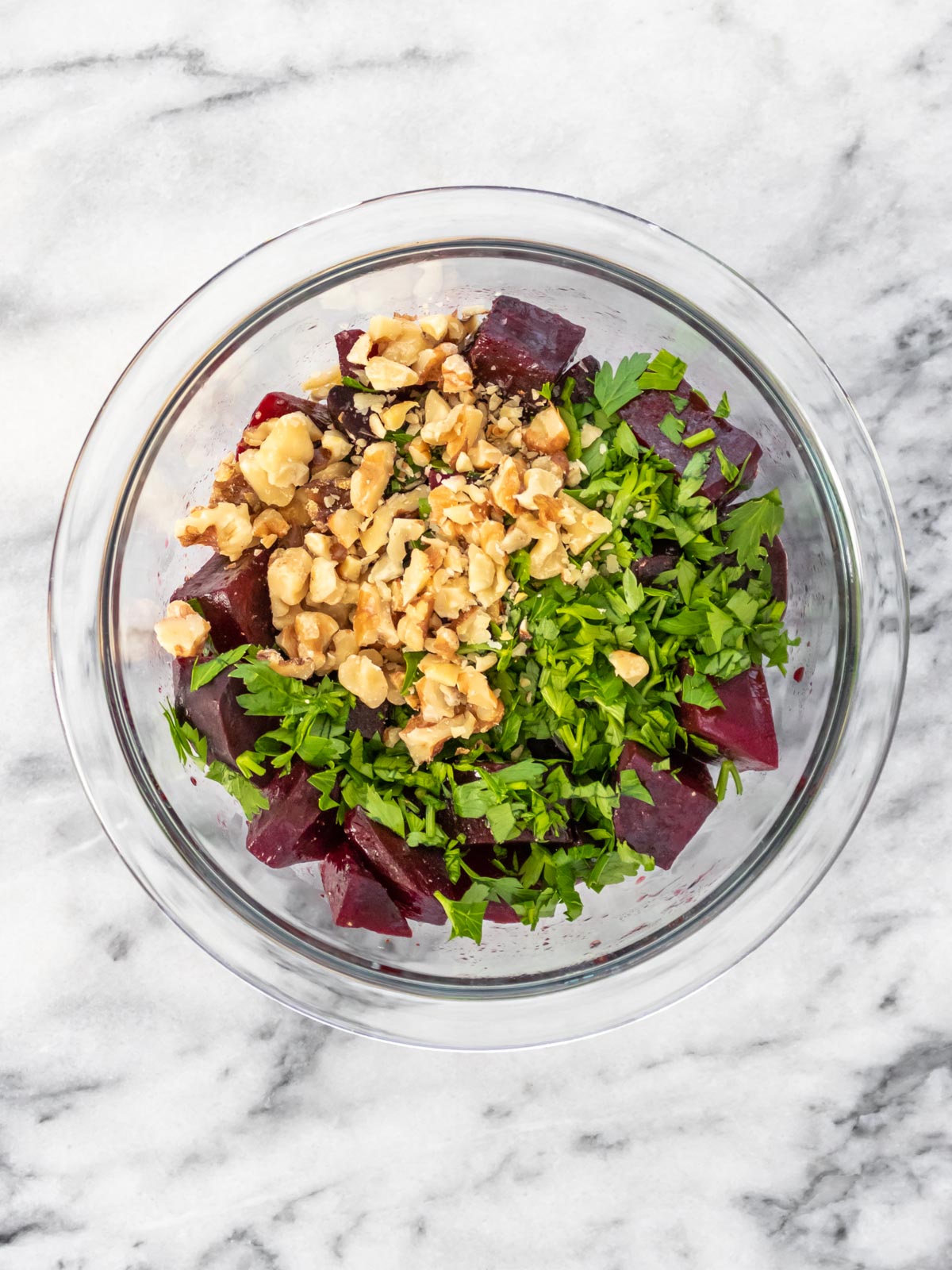 salada de beterraba cozida sendo preparada em uma vasilha com nozes e salsinha fresca picada