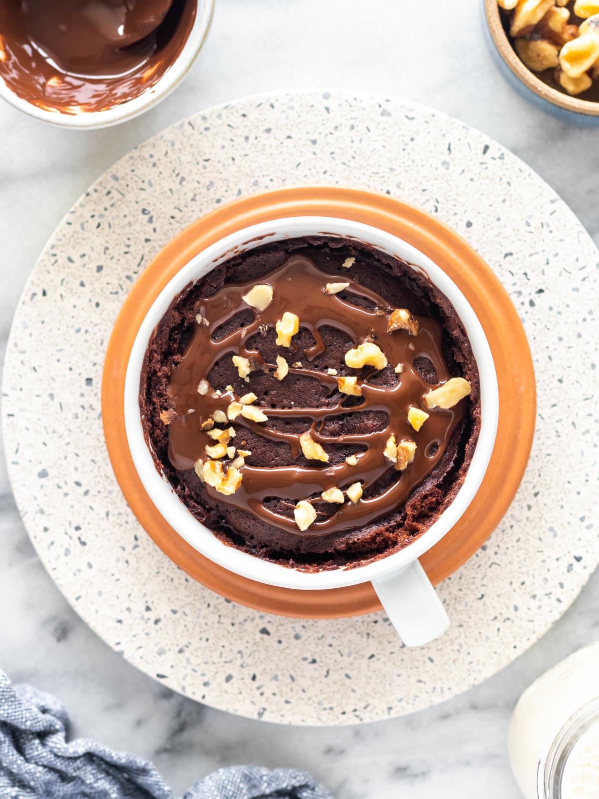 bolo de caneca vegano de cacau com cobertura de chocolate e nozes picadas