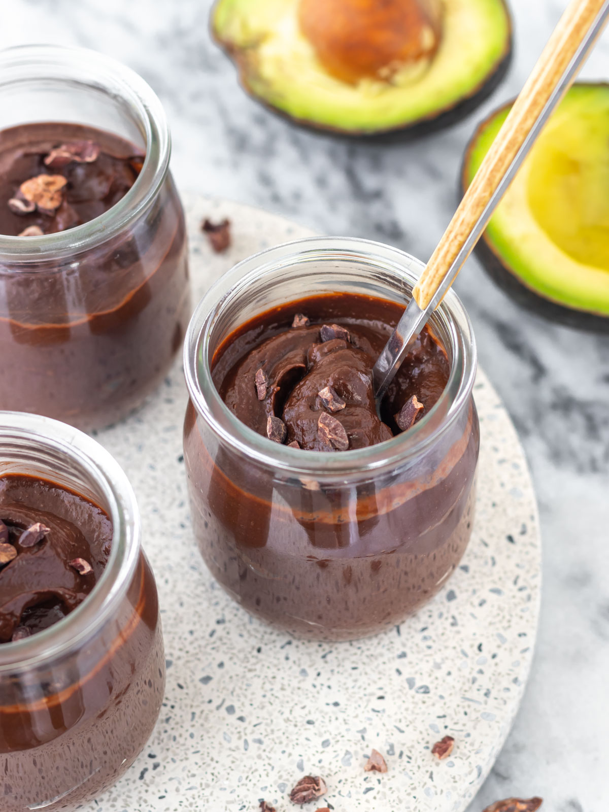 colher inserida em um pote contendo mousse de abacate com cacau