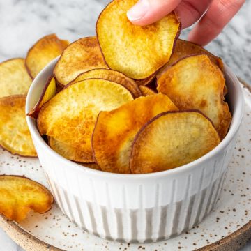 mão retirando um chips de batata-doce de um pote