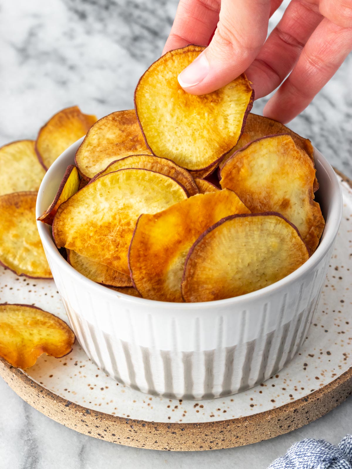 mão retirando um chips de batata-doce de um pote
