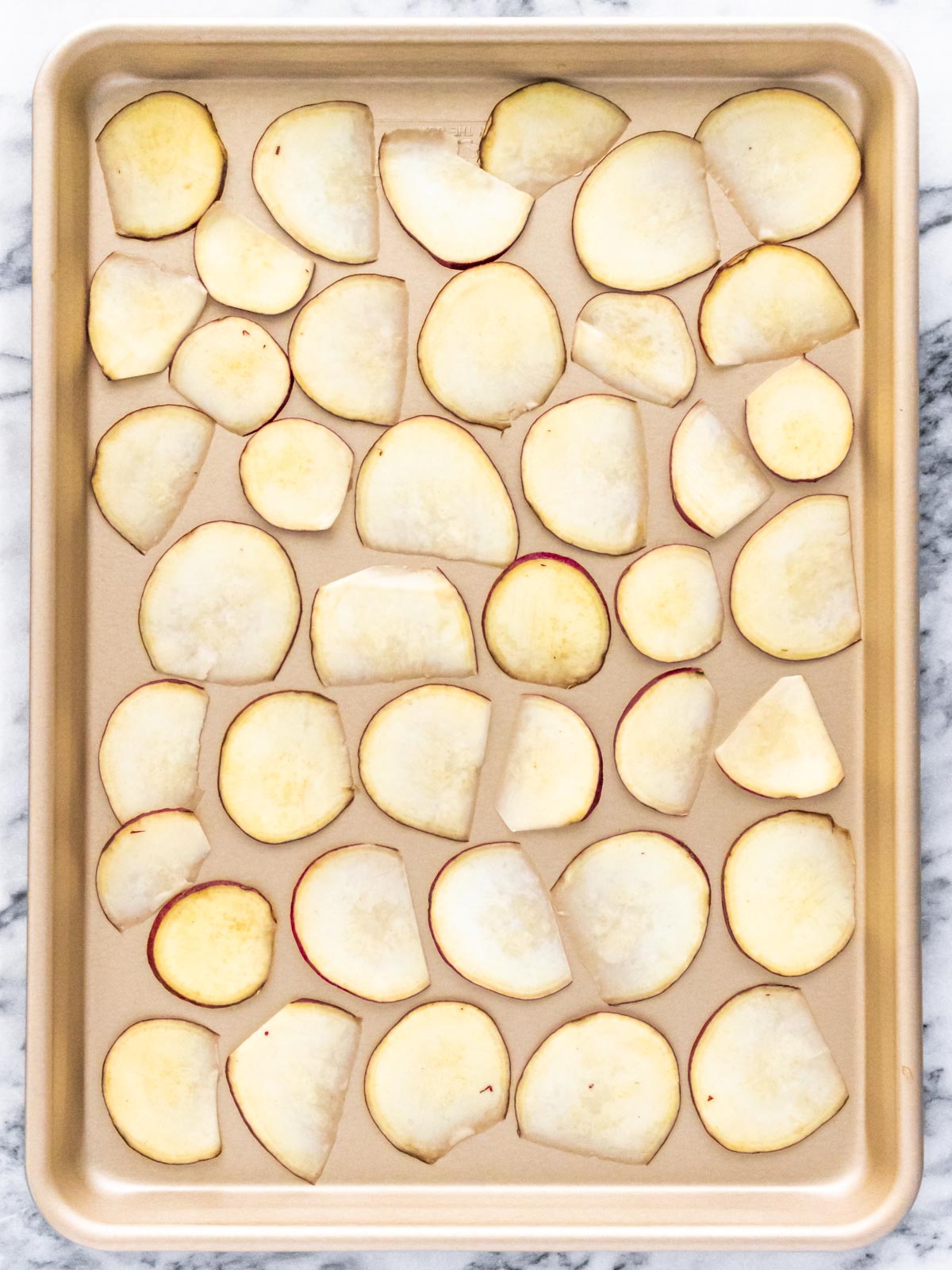 fatias finas de batata-doce espalhadas em uma assadeira