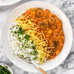 vista aérea de um prato com arroz com salsinha picada, estrogonofe de brócolis com grão-de-bico e batata palha