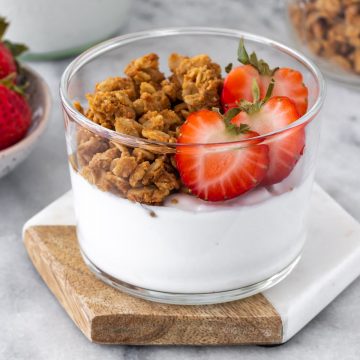 iogurte de coco caseiro servido em um pote com granola e morangos frescos cortados na metade
