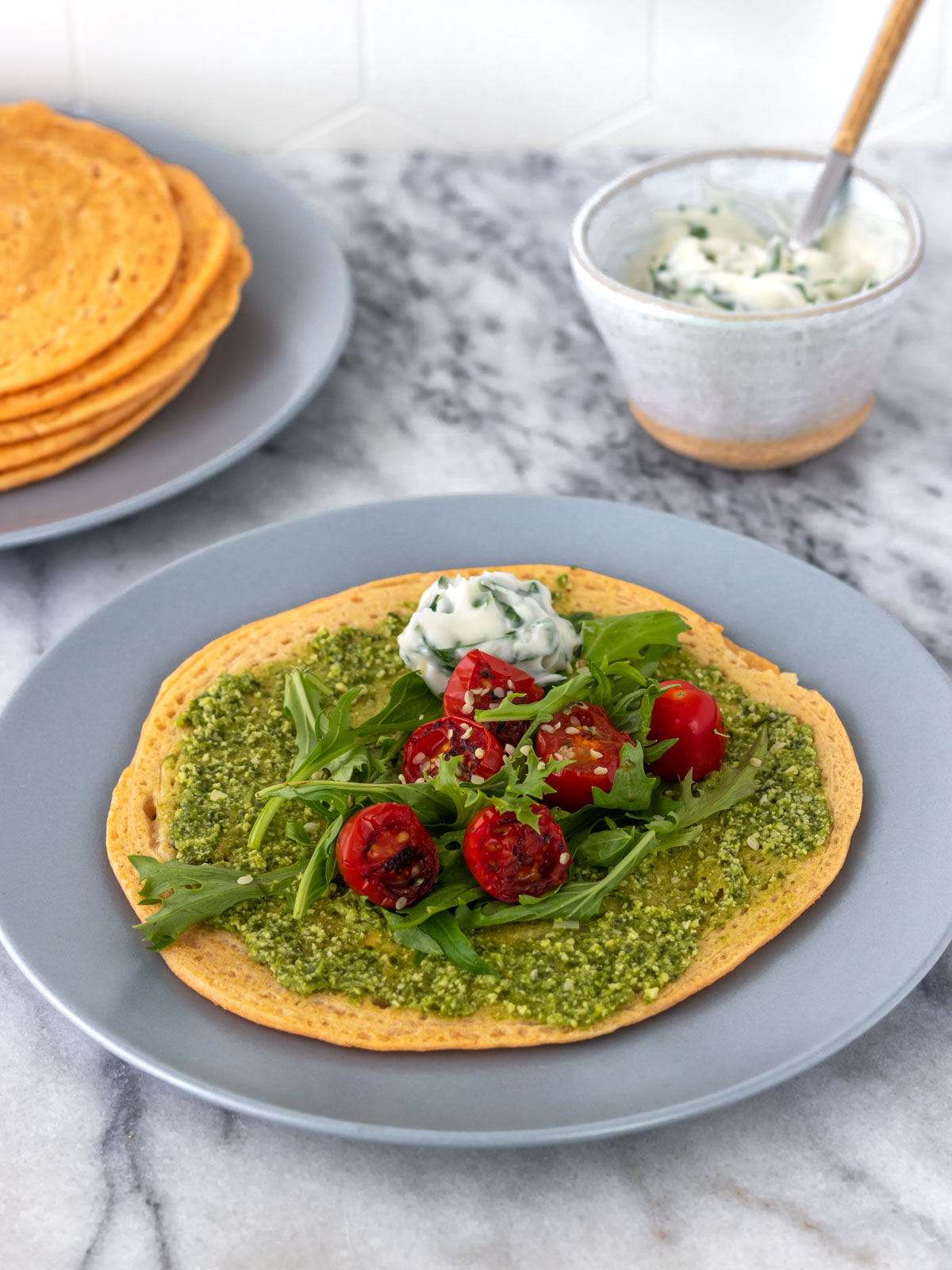 panqueca de lentilha recheada com molho pesto vegano, rúcula fresca e tomates cereja