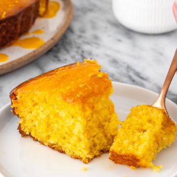 vista lateral de um pedaço de bolo de laranja com calda cortado com um garfo