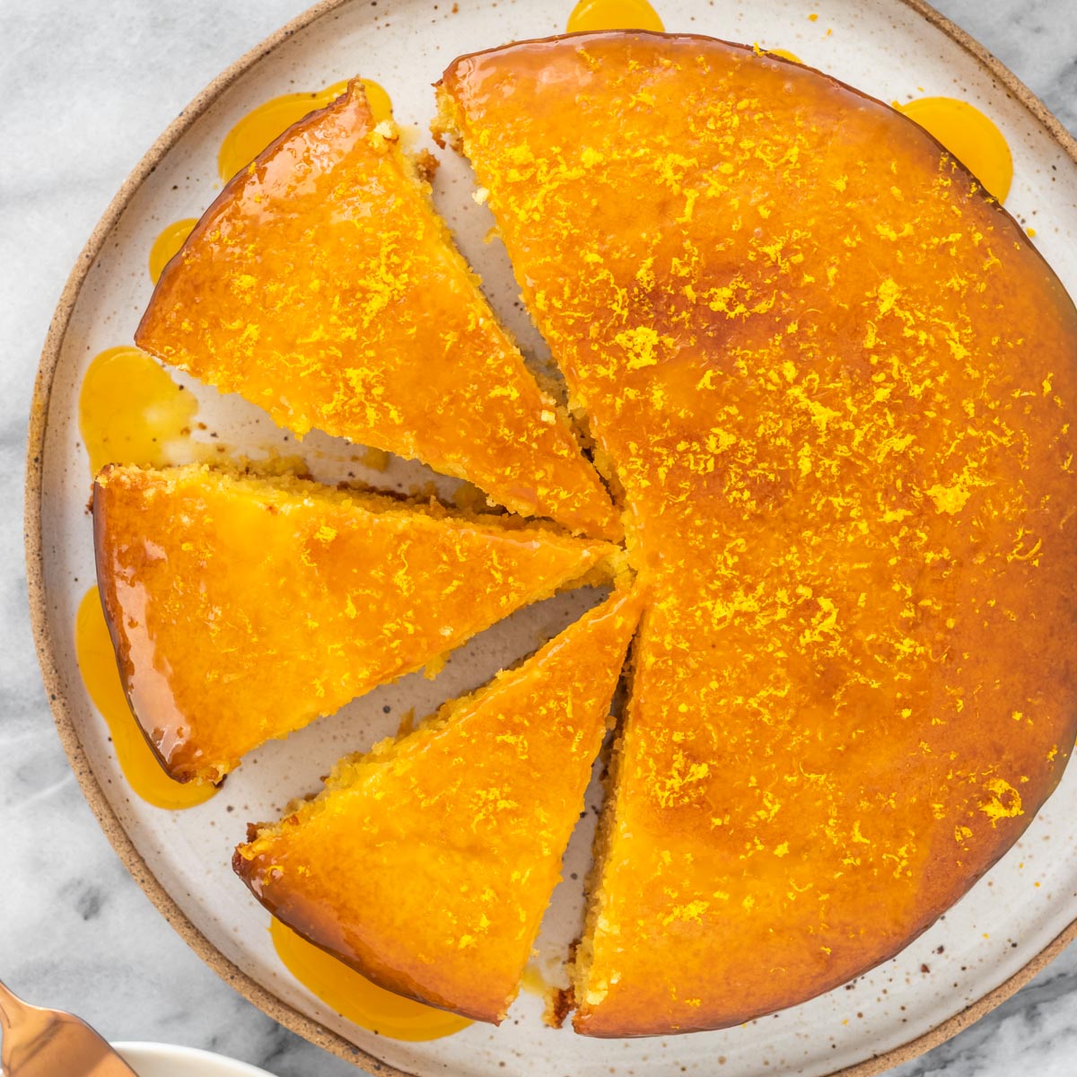 vista aérea de um bolo de laranja com calda, redondo e com 3 fatias cortadas