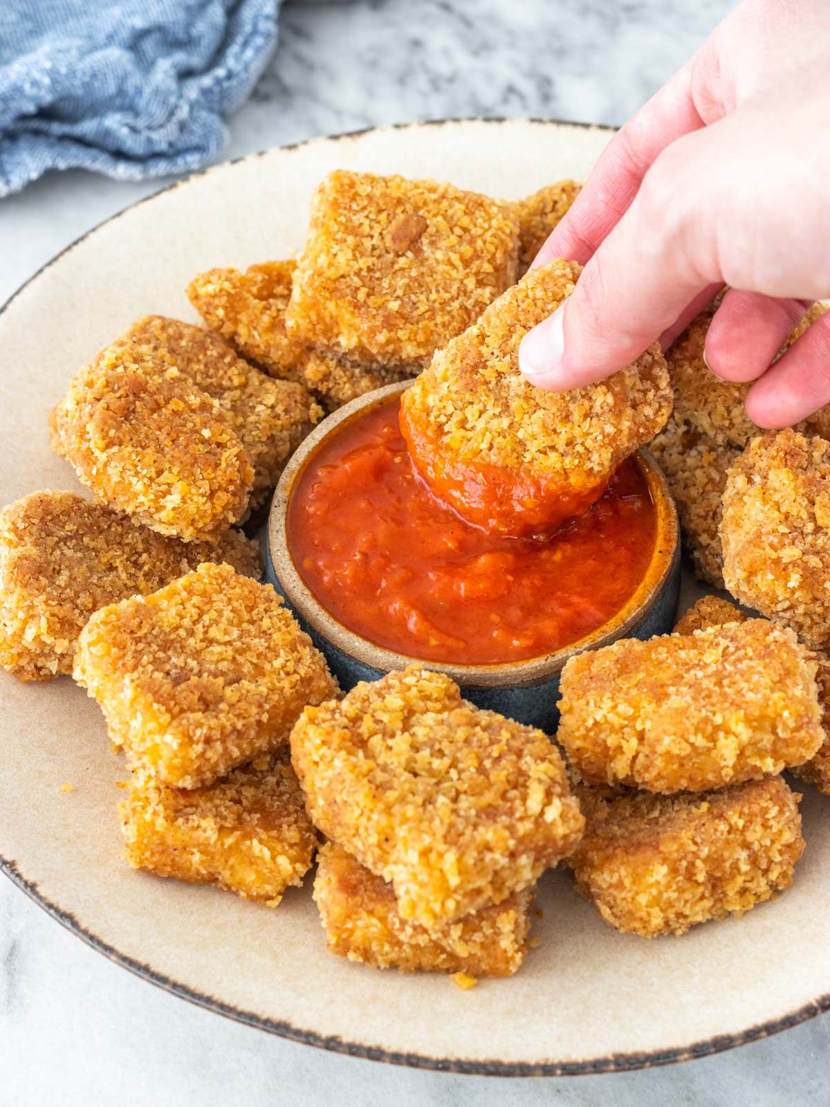 nuggets vegano sendo mergulhado em um pote de molho marinara