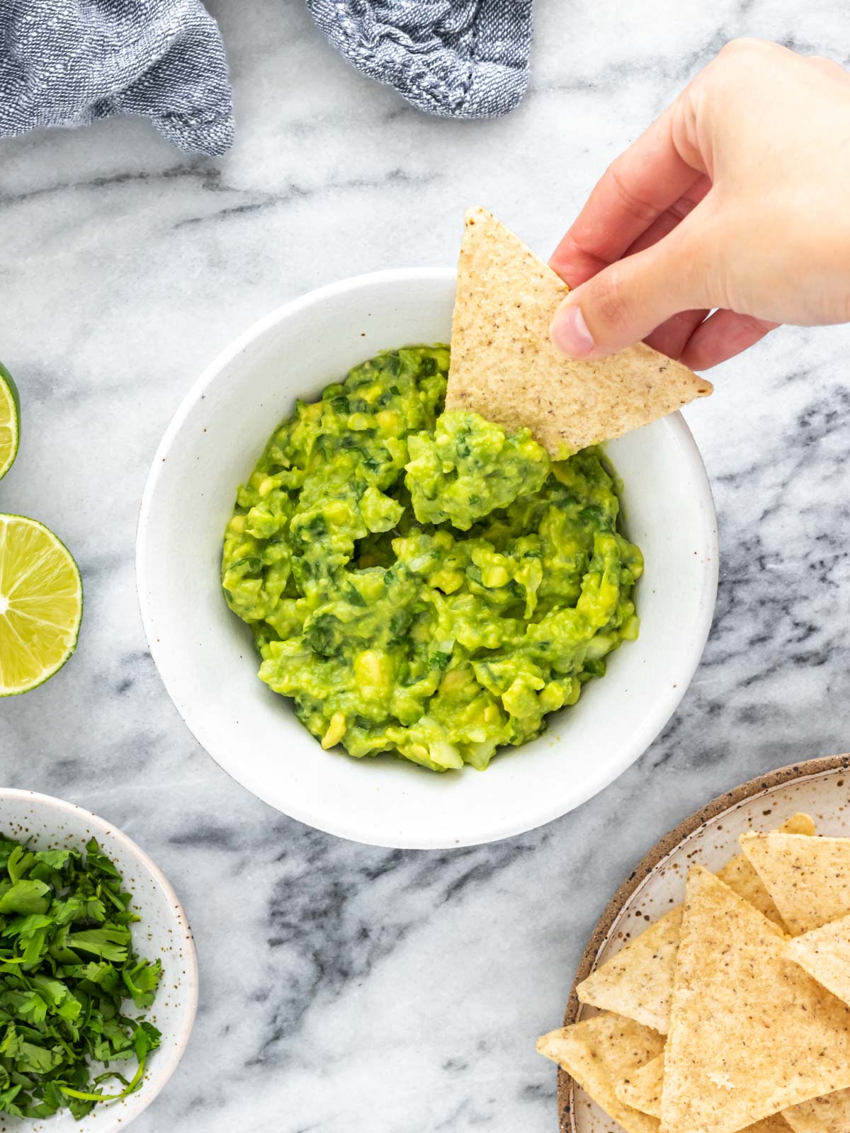 tortilla sendo inserida em um bowl de guacamole