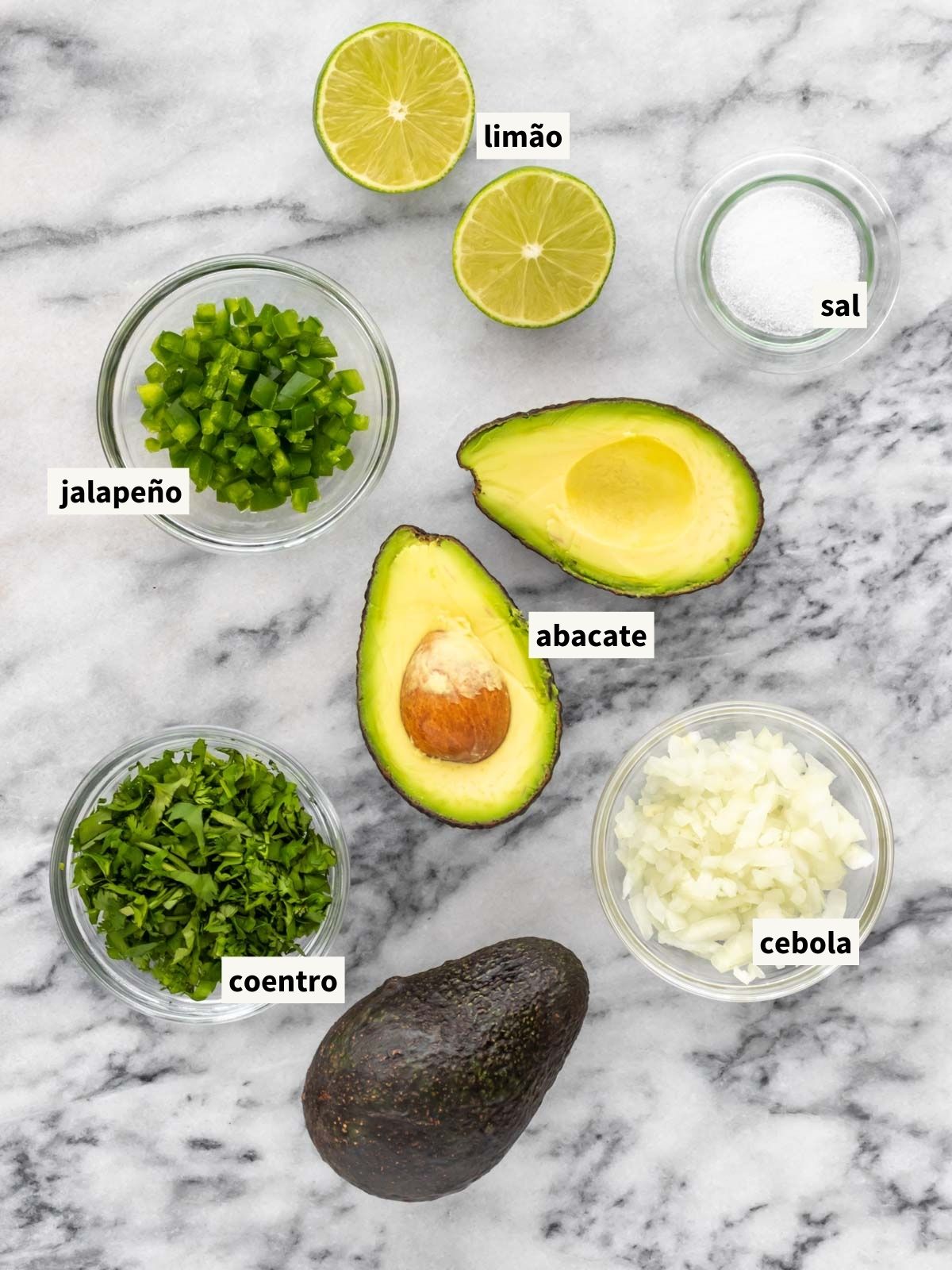 ingredientes para fazer guacamole incluindo avocado, cebola, coentro fresco, pimenta jalapeño, suco de limão e sal