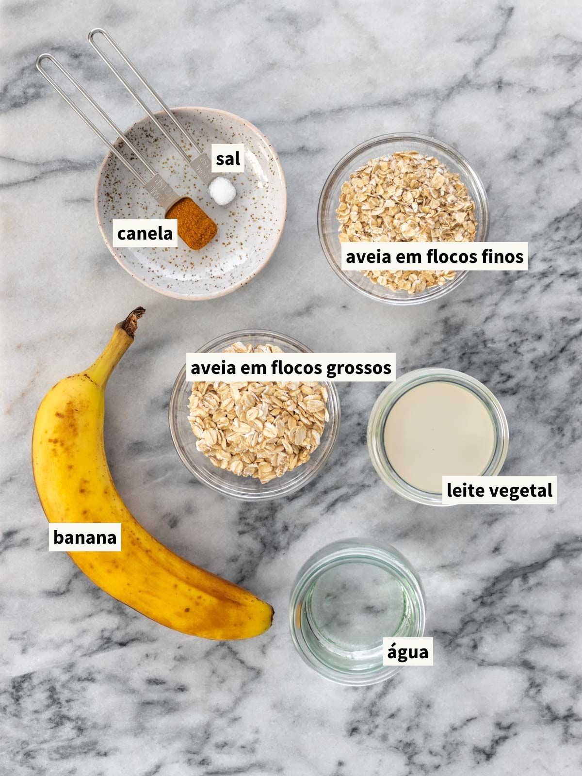 ingredientes para fazer mingau de aveia com banana, incluindo banana madura, aveia em flocos grossos, aveia em flocos finos, leite vegetal, água filtrada, canela em pó e sal