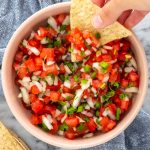 tortilla sendo inserida em um pote de pico de gallo