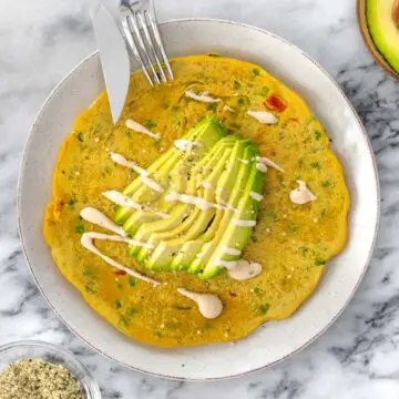 grãomelete em um prato servida com abacate, molho de tahine e sementes