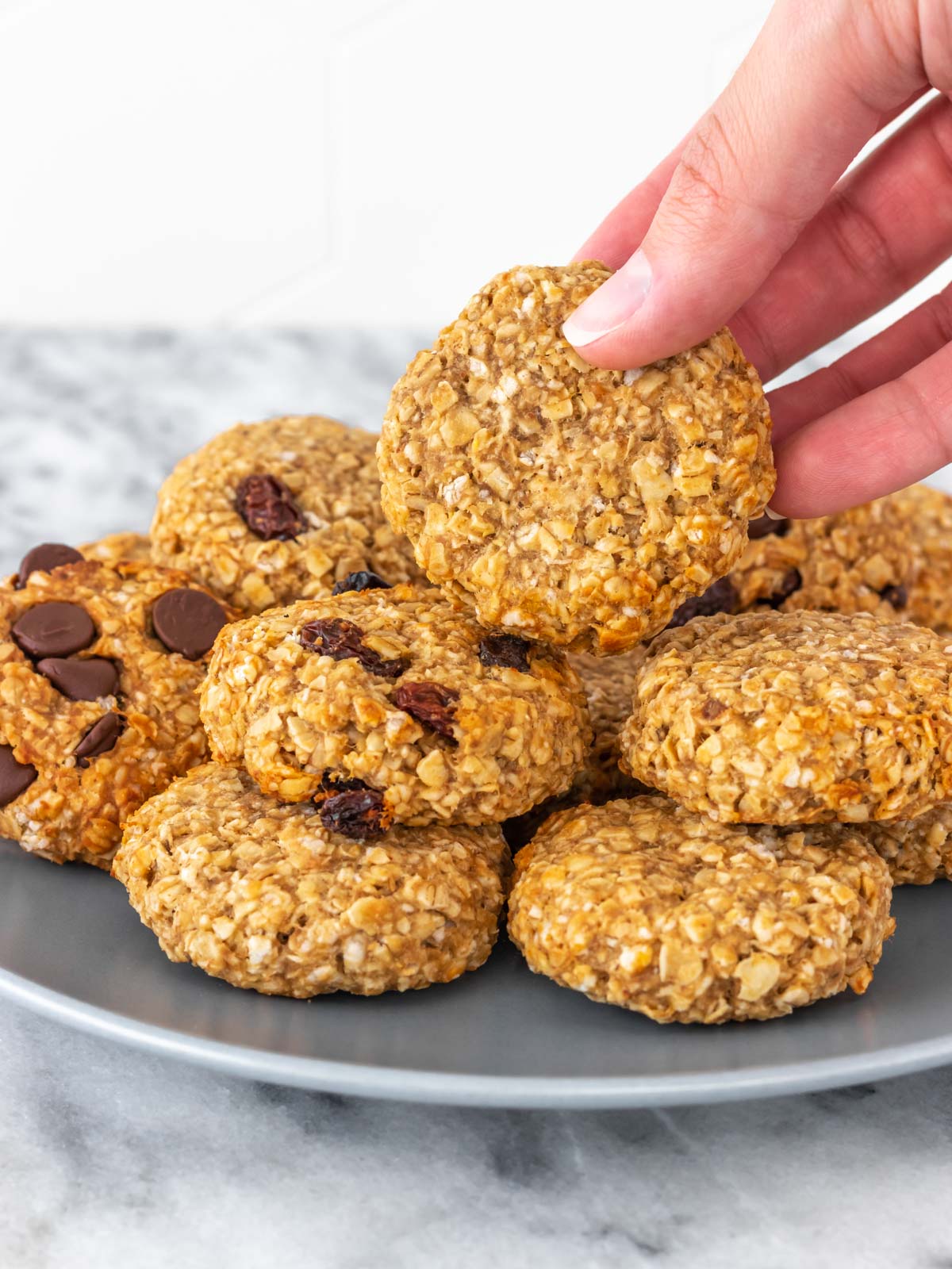 cookie de aveia sendo retirado, com a mão, de um prato com outros cookies