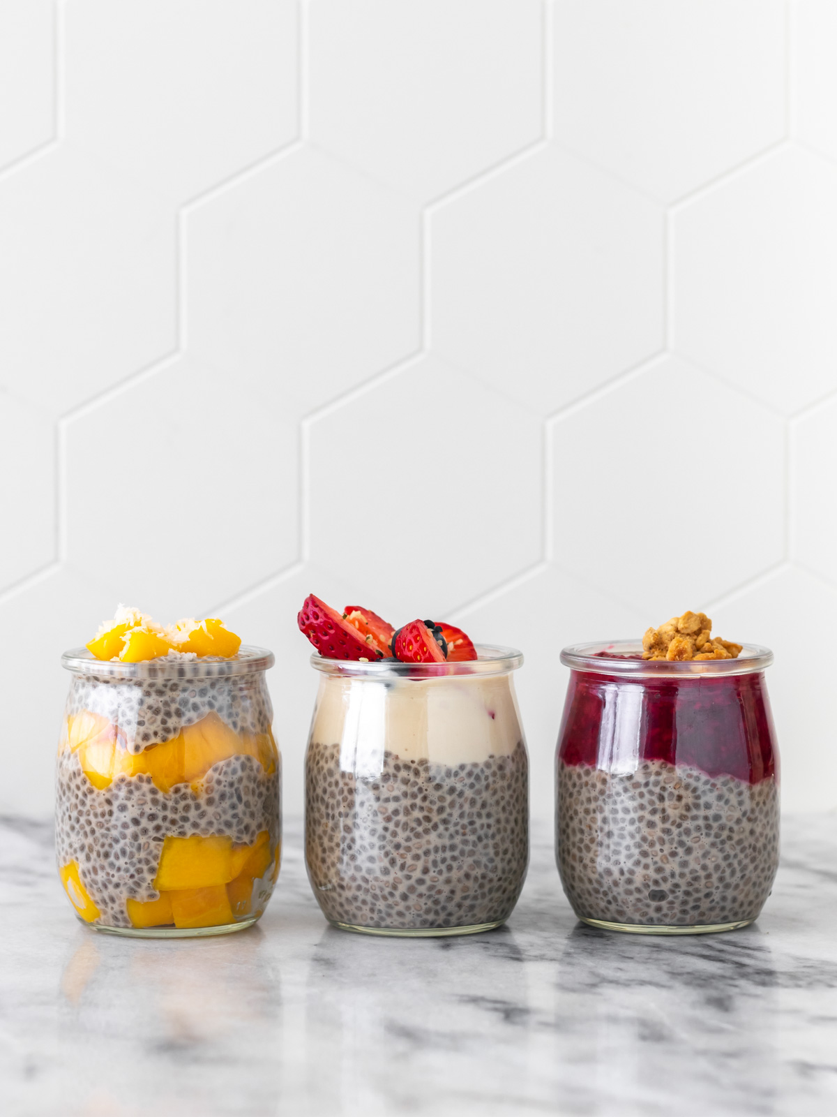 3 potinhos de pudim de chia servidos com manga e coco (1), iogurte de tofu e frutas vermelhas (2), compota de framboesa e granola de pasta de amendoim (3)