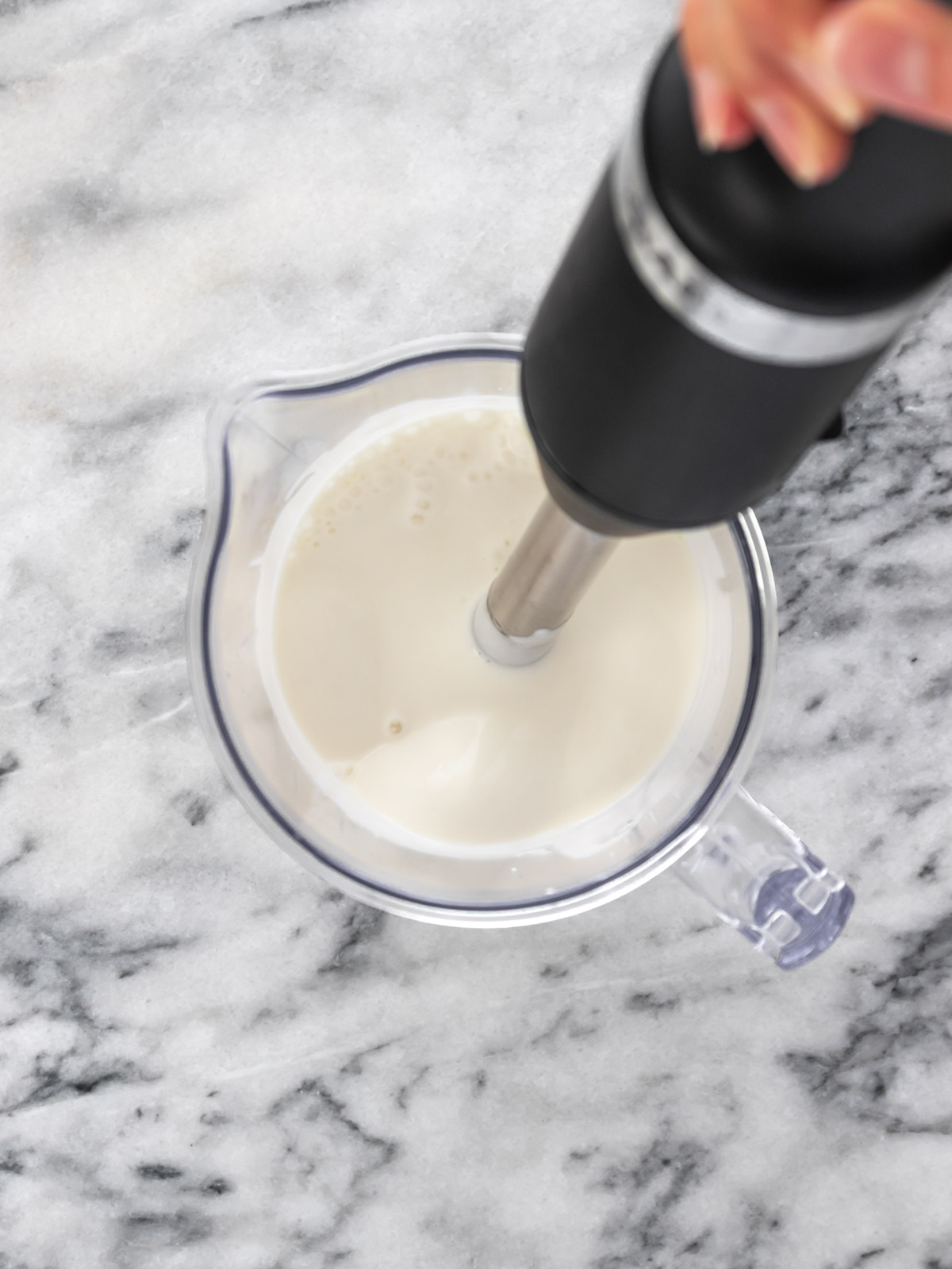 mixer de mão dentro de pote fazendo maionese vegana