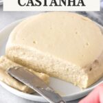 Queijo de castanha-de-caju redondo em cima de um prato. Uma faca está fatiando um lado do queijo.