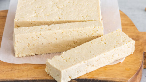 bloco de tofu caseiro cortado em cima de uma tábua, mostrando sua textura firme