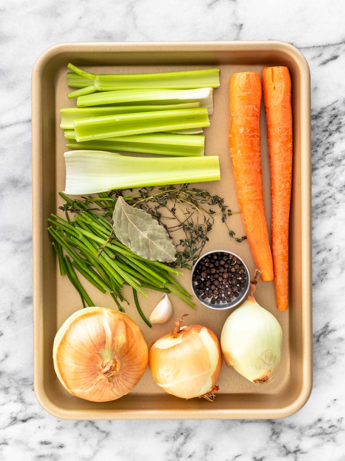 ingredientes para fazer caldo de legumes caseiro em cima de uma travessa, limpos e cortados