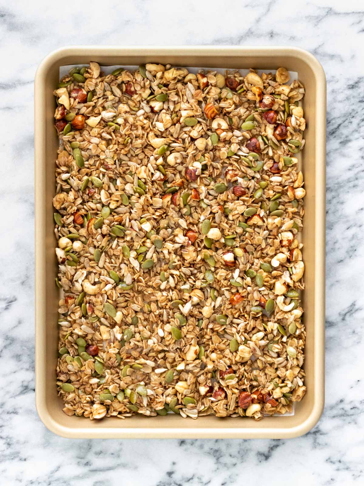 mistura de granola espalhada em uma assadeira, pronta para assar