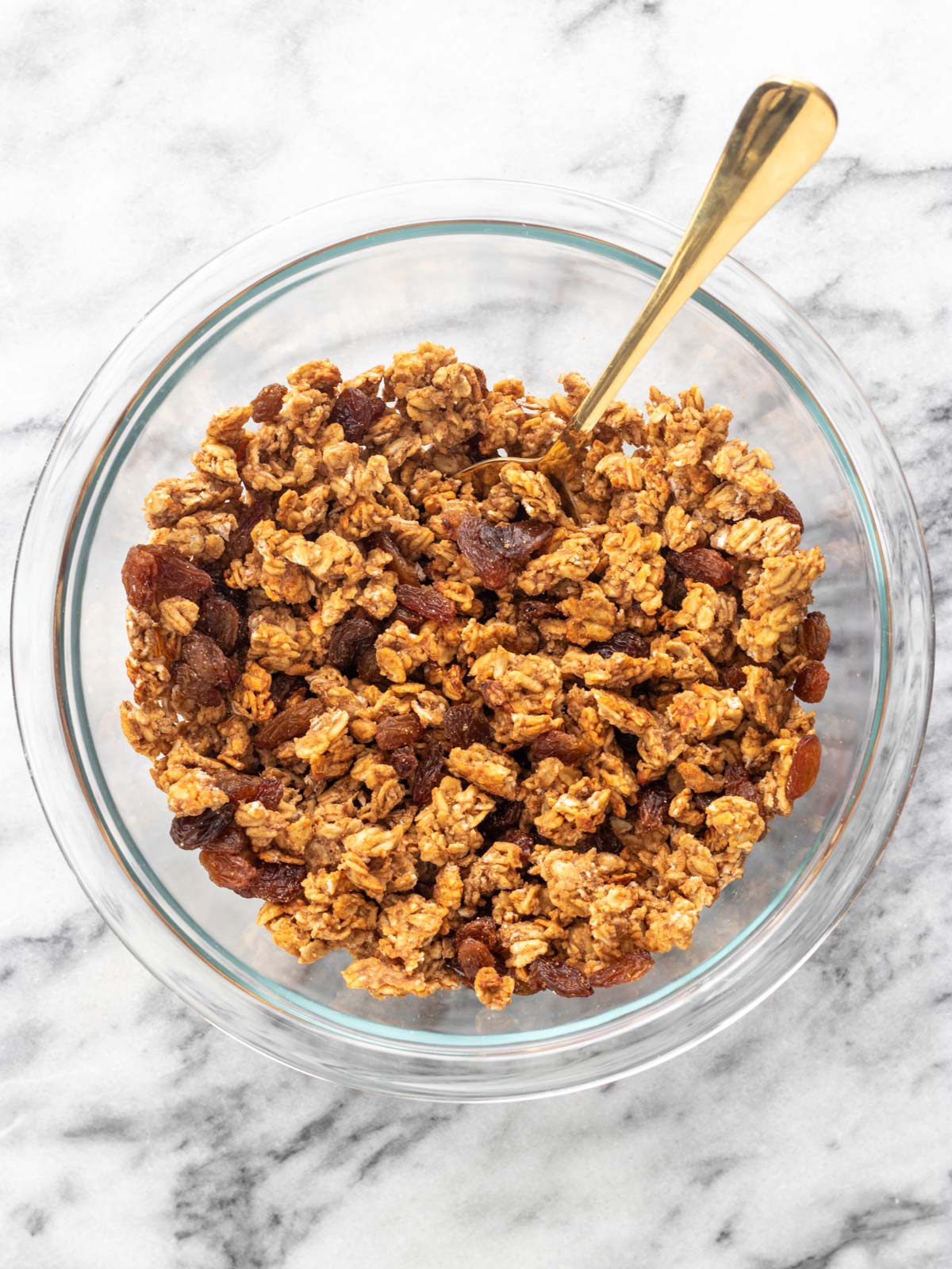 granola de banana sem açúcar em uma vasilha com uvas-passas sendo misturadas nela
