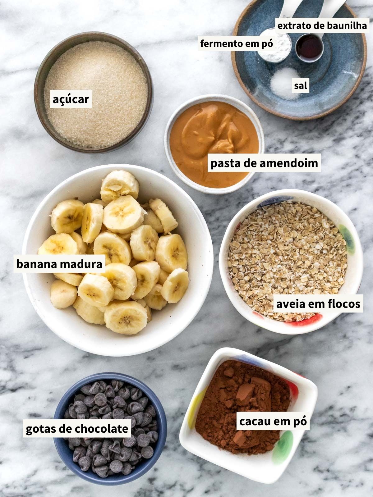 ingredientes para fazer brownie de banana, incluindo aveia em flocos finos, cacau em pó, açúcar cristal, sal, bananas maduras, pasta de amendoim natural, extrato de baunilha, fermento em pó e gotas de chocolate