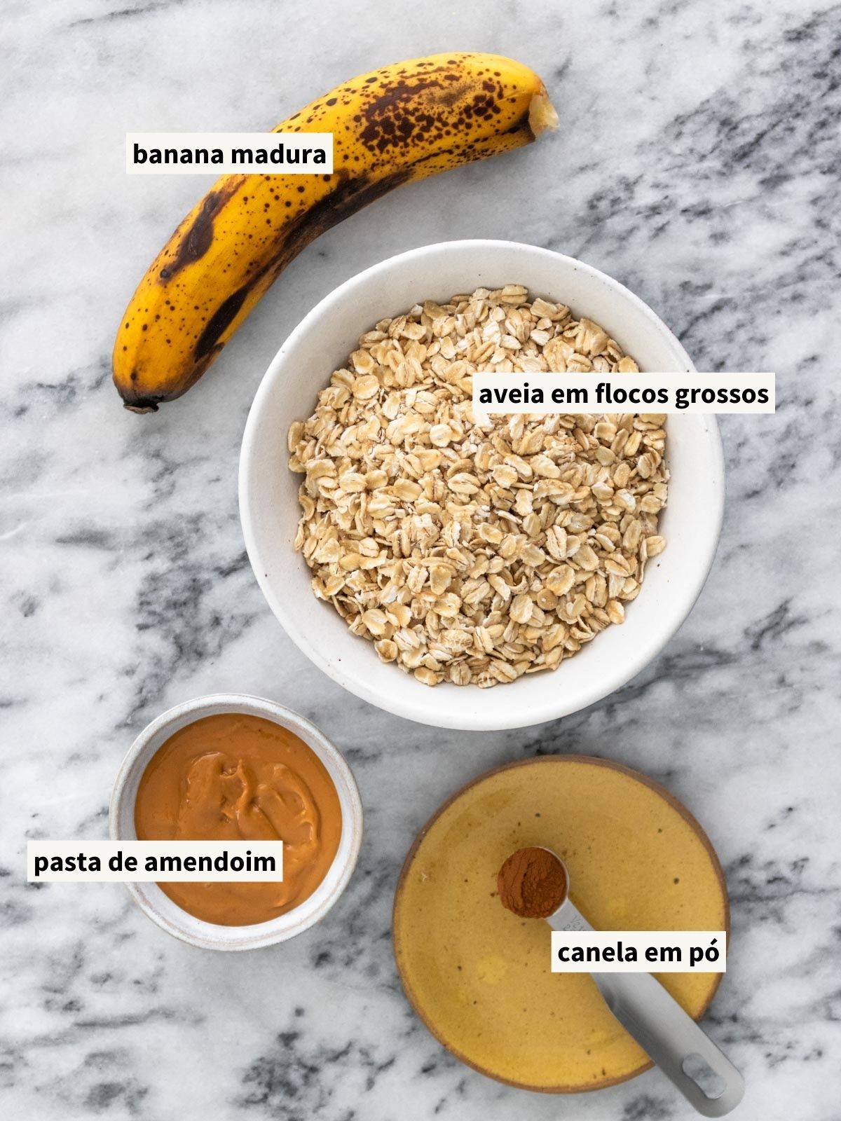 ingredientes para fazer granola sem açúcar, incluindo banana, aveia em flocos grossos, pasta de amendoim e canela em pó