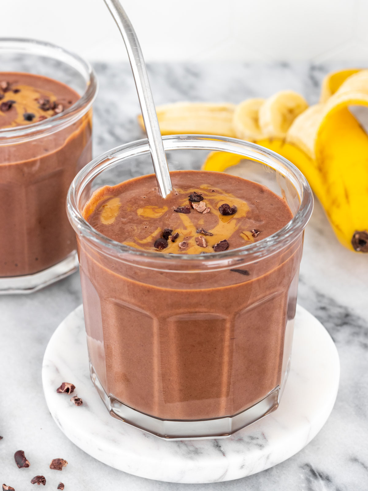 copo de vitamina de chocolate com tofu decorado com pasta de amendoim e nibs de cacau