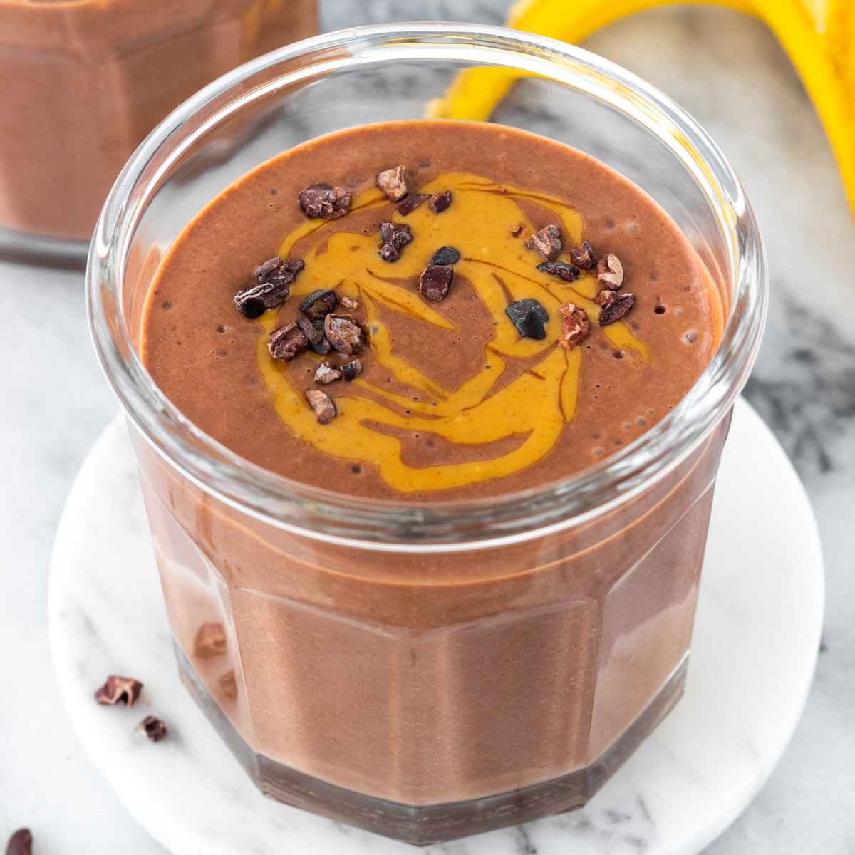 copo de vitamina de chocolate com tofu decorado com pasta de amendoim e nibs de cacau