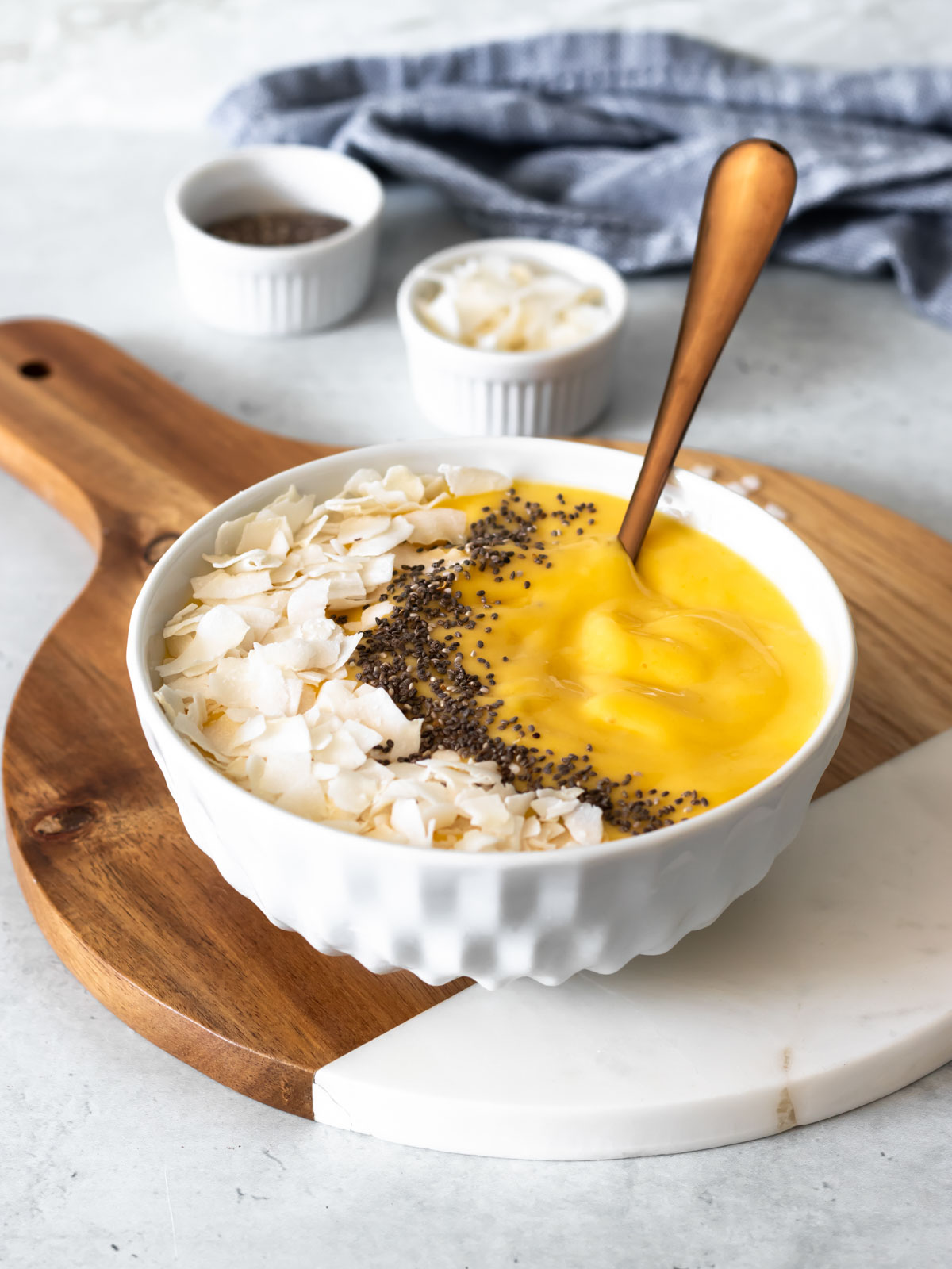 vitamina de manga servida na tigela com coco em fitas e sementes de chia