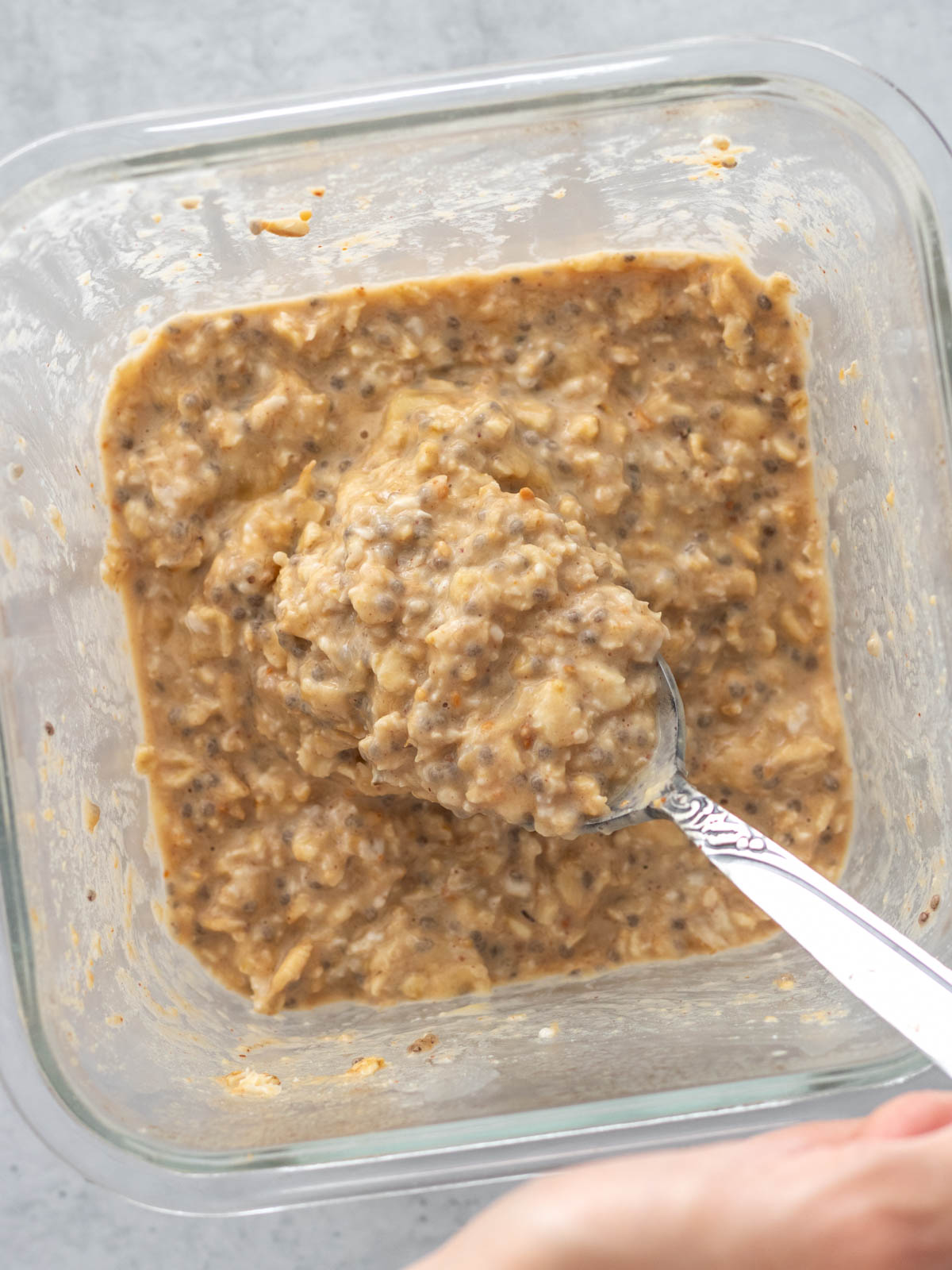 colher retirando overnight oats de banana com pasta de amendoim de pote mostrando sua textura cremosa