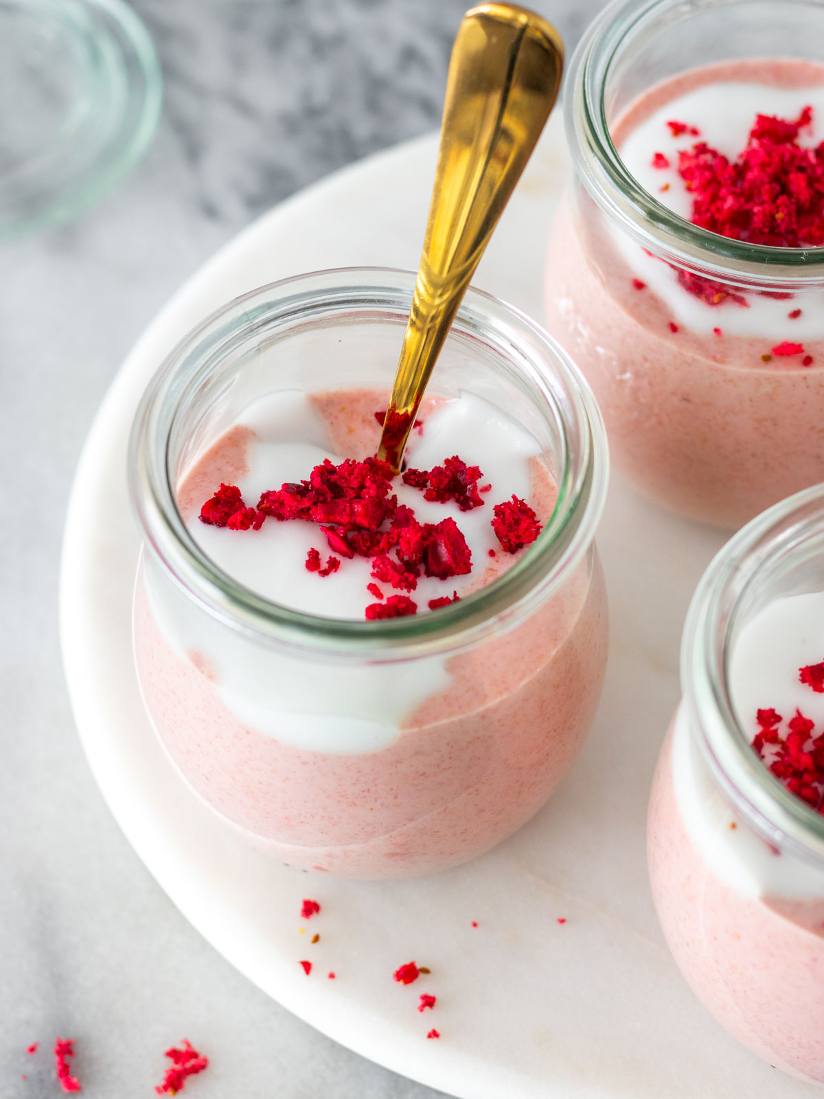 creme de aveia batido com morangos servido em um potinho com iogurte e framboesas desidratadas
