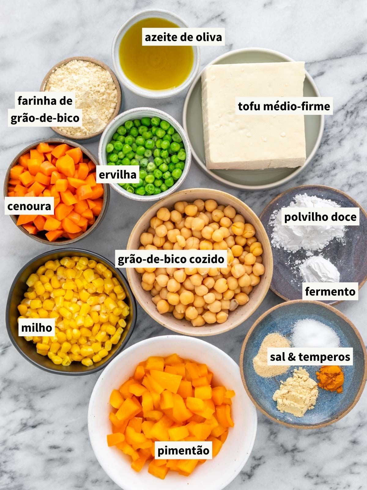 ingredientes para fazer torta de legumes vegana, incluindo tofu médio-firme, grão-de-bico cozido, azeite de oliva, sal, mostarda amarela em pó, alho em pó, cúrcuma em pó, pimenta-do-reino moída, farinha de grão-de-bico, polvilho doce, fermento químico em pó, milho, ervilha, cenoura e pimentão laranja