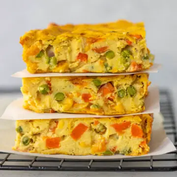 três pedaços de torta de legumes vegana empilhados e separados por um pedaço de papel antiaderente