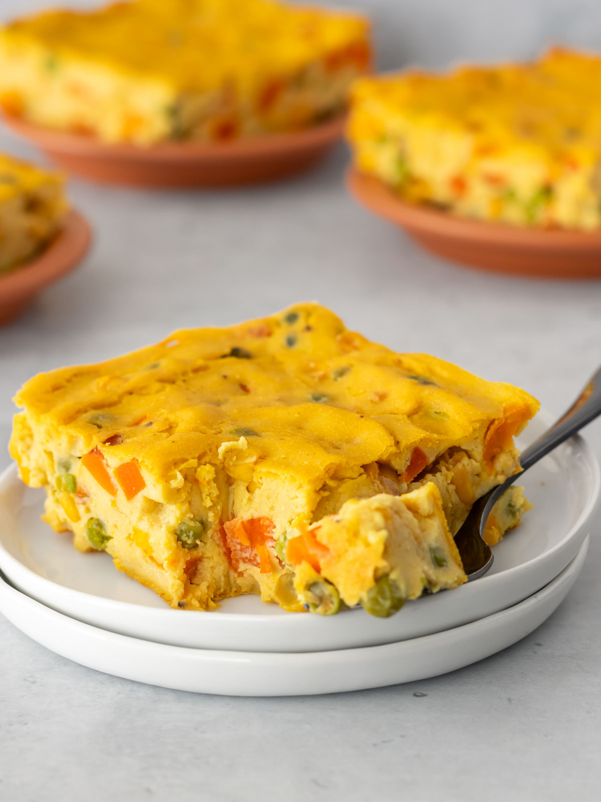pedaço de torta de legumes servido em um prato, com um garfo pegando a parte da ponta
