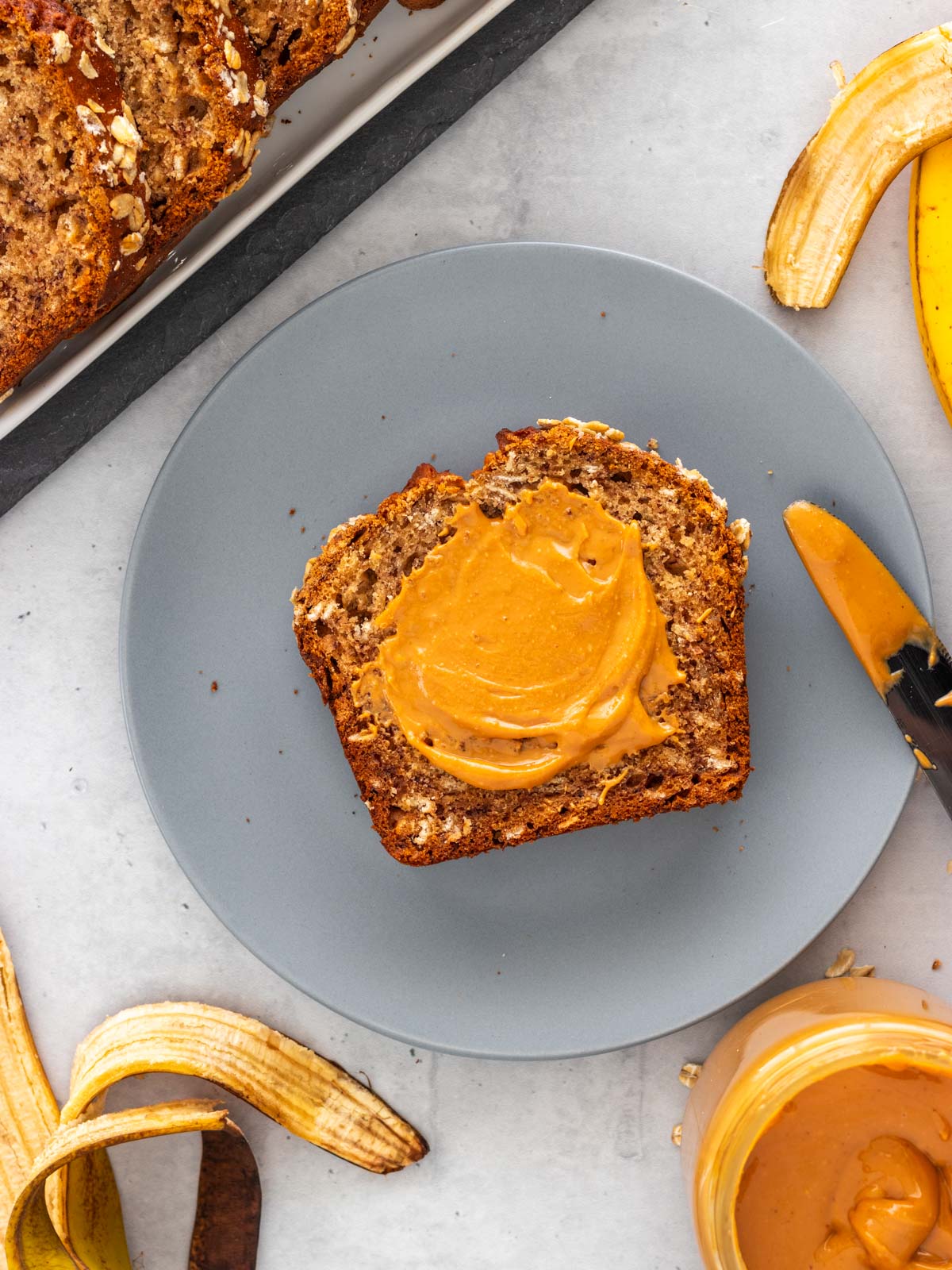 fatia de bolo de banana com aveia servido em um prato com cobertura de pasta de amendoim