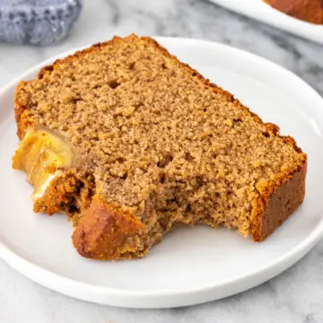 fatia de bolo de banana sem glúten mordida em cima de um prato, mostrando sua textura macia
