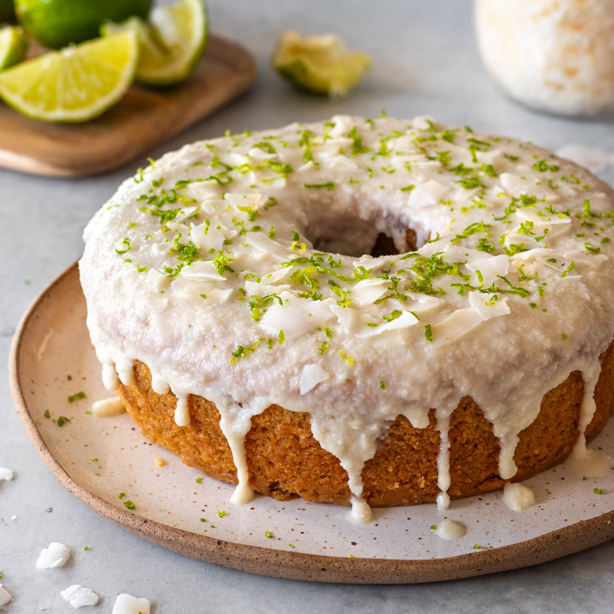 bolo de coco e limão com cobertura de manteiga de coco integral, coco em fitas e raspas de limão servido em um prato