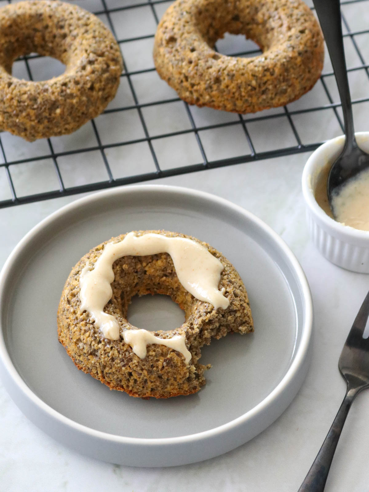 donut de aveia e chia mordido, com cobertura de pasta de amendoim e canela em pó, servido em um prato