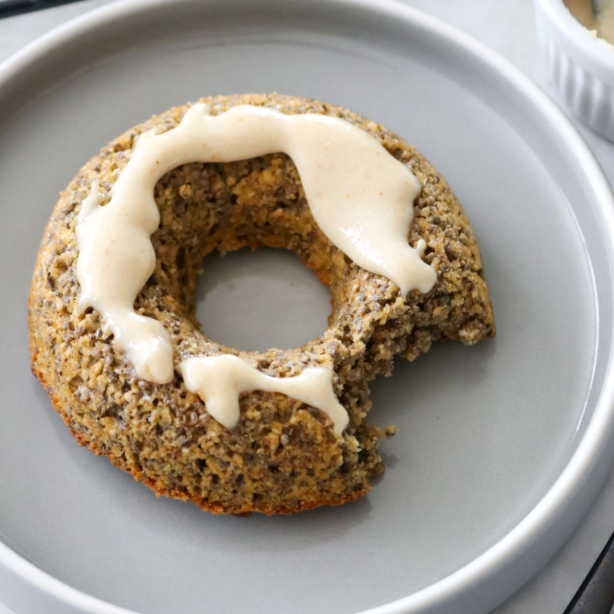 donut de aveia e chia mordido, com cobertura de pasta de amendoim e canela em pó, servido em um prato