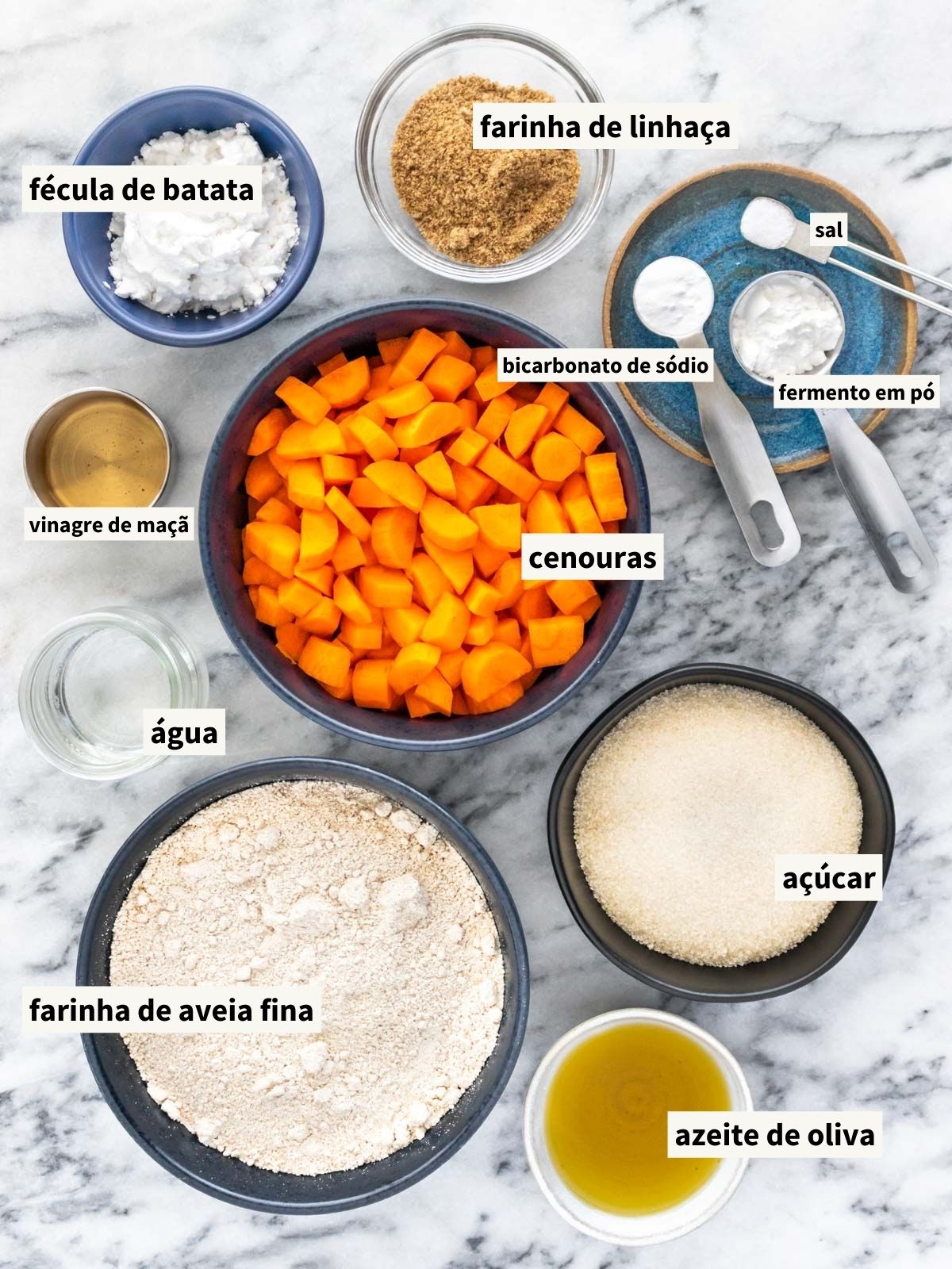 ingredientes para fazer bolo de cenoura sem glúten, incluindo farinha de aveia fina, cenoura, azeite de oliva, açúcar, farinha de linhaça, água filtrada, sal, vinagre de maçã, fécula de batata, fermento químico em pó e bicarbonato de sódio